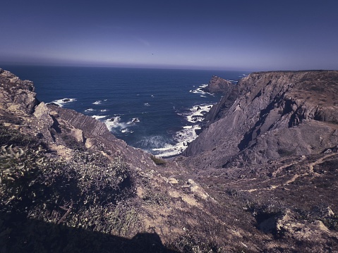 An aerial view of a landscape featuring cliffs and mountains surrounding a large body of crystal blue water