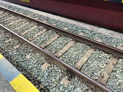 Steel train rail or railroad track on the grey stone pebbles or gravel at train station