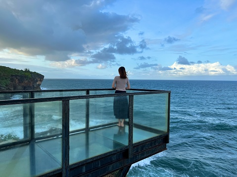 Girl Standing On The Top of Glass Platform Beside The sea watching Ocean or Sea or Horizon or Coastline