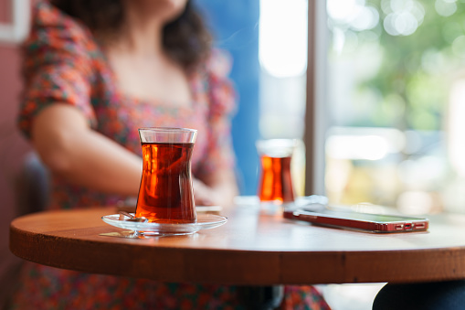 Two people having Turkish tea and using mobile phone in a cafe.