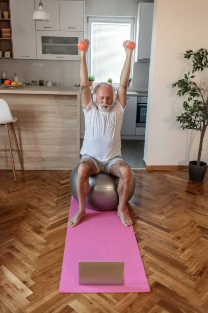 istock Middle age man with beard training and stretching doing exercise at home looking at sport video on his laptop. 1505599419