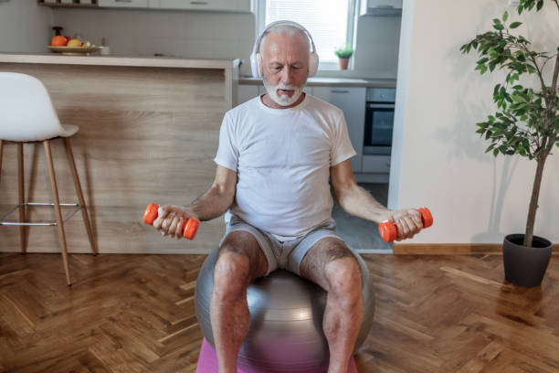 istock Cropped shot of a senior man watching tutorial on his laptop, doing exercise with dumbbells while listening the music at home. 1505599602