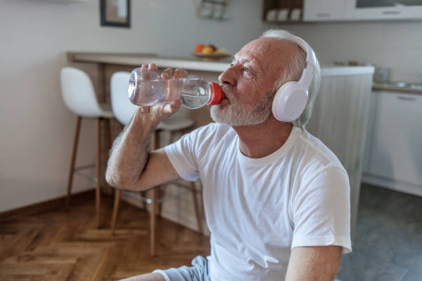 istock Handsome senior men resting and drinking water while training, he is listening to music at home during the day. 1505599951