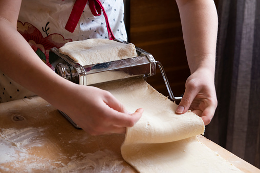Automation of the Process of Working with the test at home.The girl rolls out the dough using a pasta dough rolling machine. it is easy and not difficult to Cook Sfogliatelle. real people