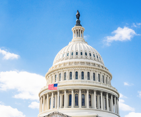 The stars and stripes flying outside the famous dome of the US Capitol Building in Washington DC.