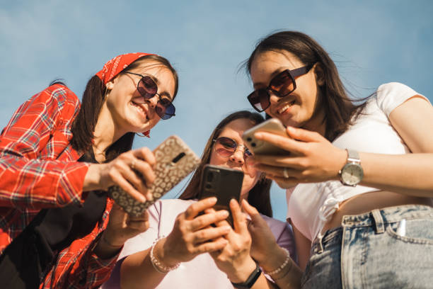 istock Group of young people using mobile phone device standing together outdoors. Millennial friends addicted to social media app, betting or playing video game on platform online. 1505614012