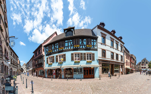 Kaysersberg, France - June 23, 2023: A picturesque colorful street of half-timber buildings with shops and cafes in the village of Kaysersberg in Vosges region.