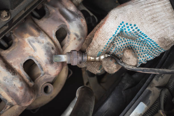 Auto mechanic pulled oxygen sensor or lambda probe for diagnostics at car service station stock photo