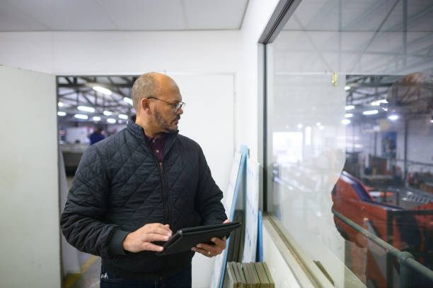 istock Manager monitoring progress from a window in a huge warehouse holding a tablet 1505641911