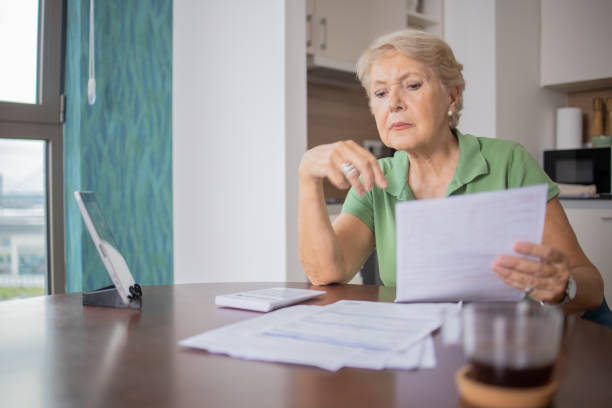 istock Senior woman using calculator while going through bills and home finances 1505642816