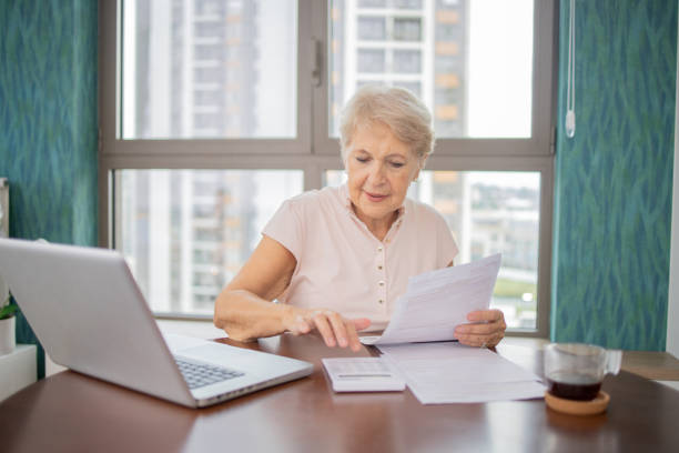 istock Senior woman using calculator while going through bills and home finances 1505642819