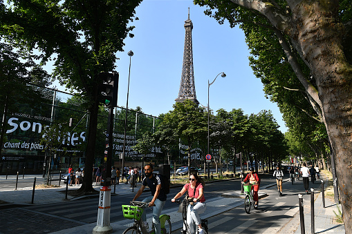 Paris, France-06 28 2023: People riding bicycles in a street of  Paris, with a view of the Eiffel Tower in the background, France.