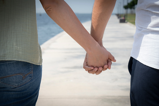 Cropped shot of a couple holding hands outdoors