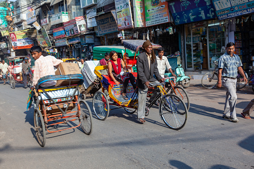 New Delhi, India - November 17, 2011: streetlife at oldest market Chandni Chowk in old Delhi. A rickshaw driver w transports passengers with his bicycle rickshaw.