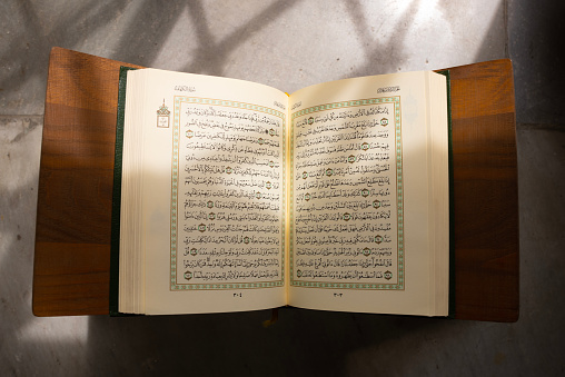The holy Qur'an.\nTop view, open page of holy book al qur'an on white background.