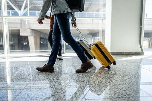 Low section of a man walking with suitcase at airport