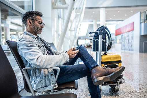 Mature man using mobile phone in waiting room at the airport