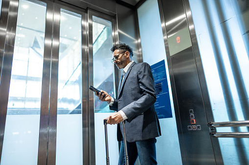 Businessman using mobile phone inside of elevator