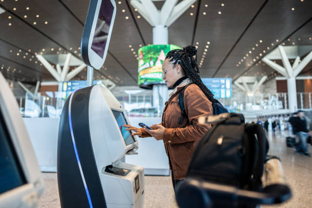 istock Young woman using self service check-in machine while use phone at the airport 1505727605