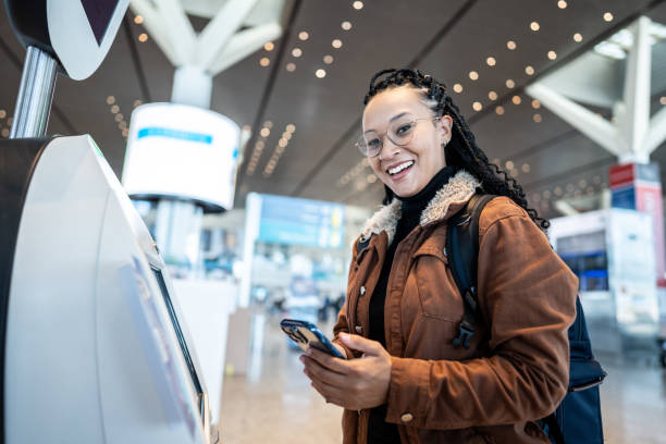 istock Portrait of a young woman using self service check-in machine while use phone at the airport 1505727607