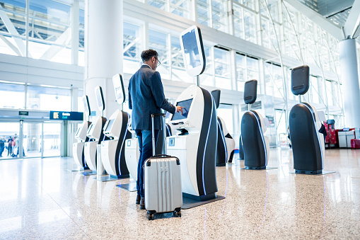 Rear view of a businessman using self service check-in machine at the airport