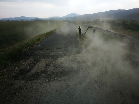 A freshly laid tarmac on a new cycle path disappearing on a windy and dusty summer evening.
