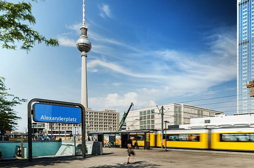 Iconic Alexanderplatz subway station: bustling hub, vibrant streets, modern urban atmosphere, with TV Tower and yellow tram.