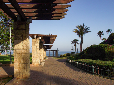 canopies from wooden lattices on benches in the park. sun protection. walking area near the sea. Netanya. Israel