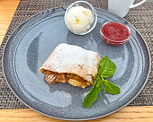 Apple strudel and ice cream with strawberry topping.