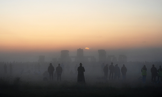 Summer Solstice dawns  at the ancient Stonehenge stone circle with silhouettes of revellers