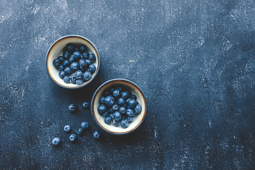 Fresh juicy blueberries in plates on a dark background top view.