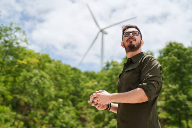 Man using remote control next to wind turbines and solar panels. stock photo
