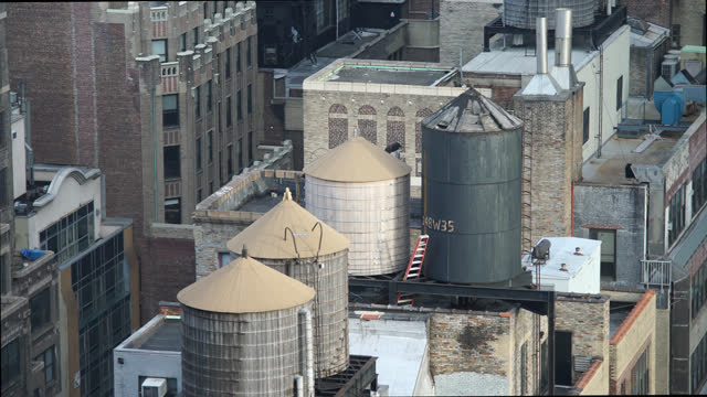 Pidgeon flying from rooftop Manhattan NYC historic wooden water tanks day