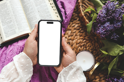 Phone in hands with isolated screen on the background of the bible , space for text.