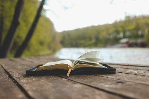istock Open Bible on a wooden board near the river 1505899463