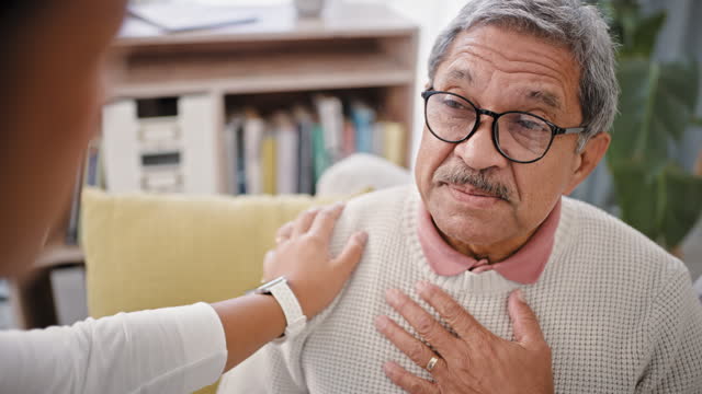 Chest pain, sick and senior man at a consultation by a doctor in a clinic for medical emergency. Cough, heart attack and elderly male person in retirement with lung infection in hospital for checkup.