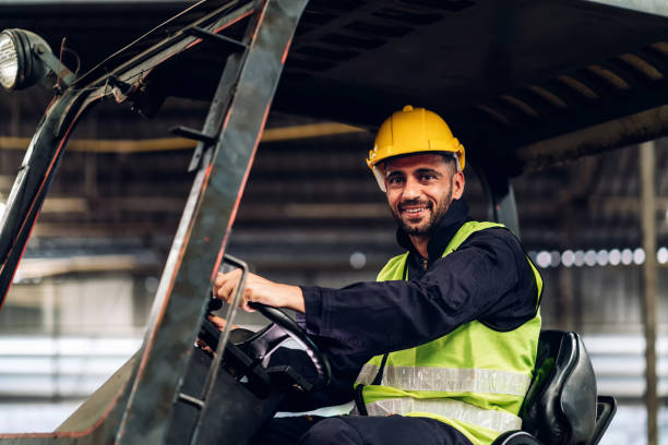 istock Man worker at forklift driver happy working in industry factory logistic ship. Man forklift driver in warehouse area. Forklift driver sitting in vehicle in warehouse 1505966584