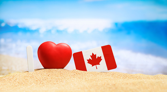 I love Canada. Flag of Canada on the beach with a red heart. vacation and travel concept.