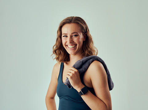 Portrait of happy young caucasian woman wearing sports bra and fitness tracker looking at camera in studio
