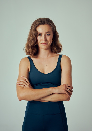 Young caucasian woman wearing sportswear looking at camera with arms crossed in studio