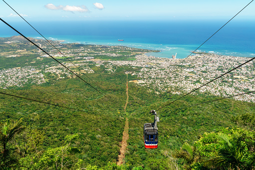 View of Puerto Plata, forest, ocean, and the cable car from the top of Mount Isabel de Torres - cable car has partly descended. In the Dominican Republic.