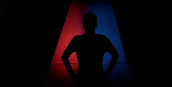 A silhouette of a person is seen illuminated by the ambient blue and red light in the background