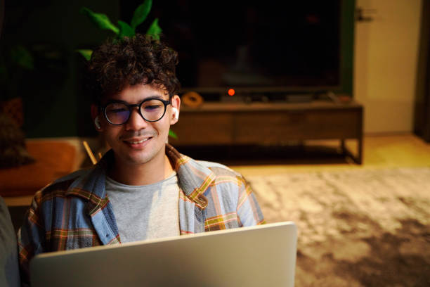 istock Happy young multiracial man wearing eyeglasses using laptop on sofa at home 1506118445