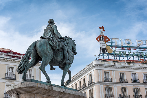 Madrid, Spain - June 20, 2023: View of the equestrian sculpture of Carlos III and the advertisement for Tio Pepe sherry in Puerta del Sol square in Madrid. Carlos III is traditionally known as \