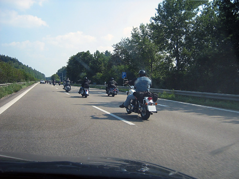 Many motorcyclist bikers ride on the track in perspective. Road trip of strong people. Rear view from the car