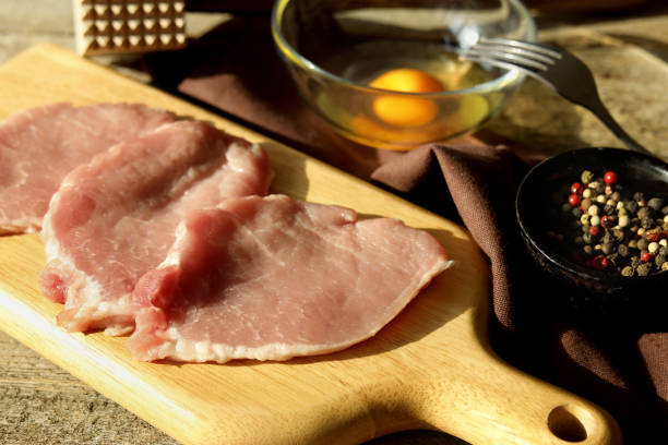 istock Cooking schnitzel. Raw pork slices, egg and peppercorns on table, closeup 1506163254