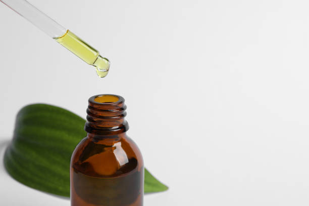 istock Dripping cosmetic oil from pipette into bottle on white background, closeup. Space for text 1506166442