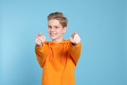 Portrait of smiling teenage boy on light blue background