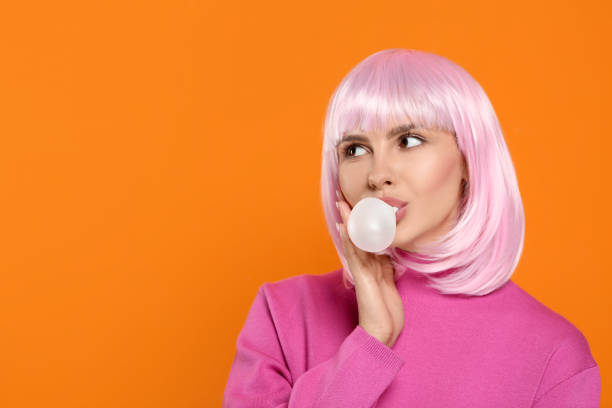 istock Beautiful woman blowing bubble gum on orange background, space for text 1506179421