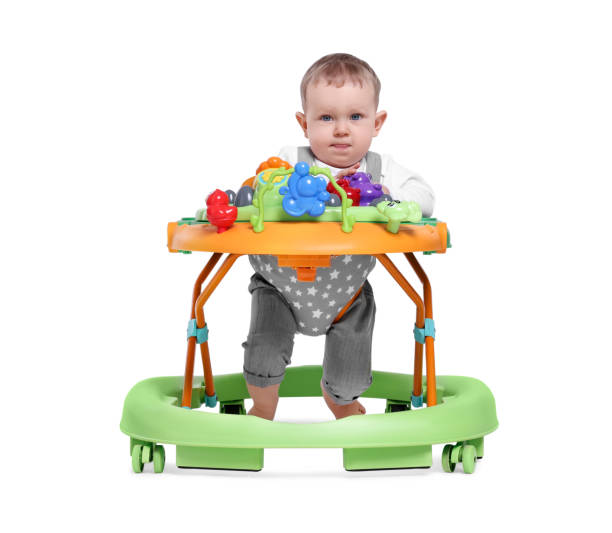 istock Cute little boy making first steps with baby walker on white background 1506179957
